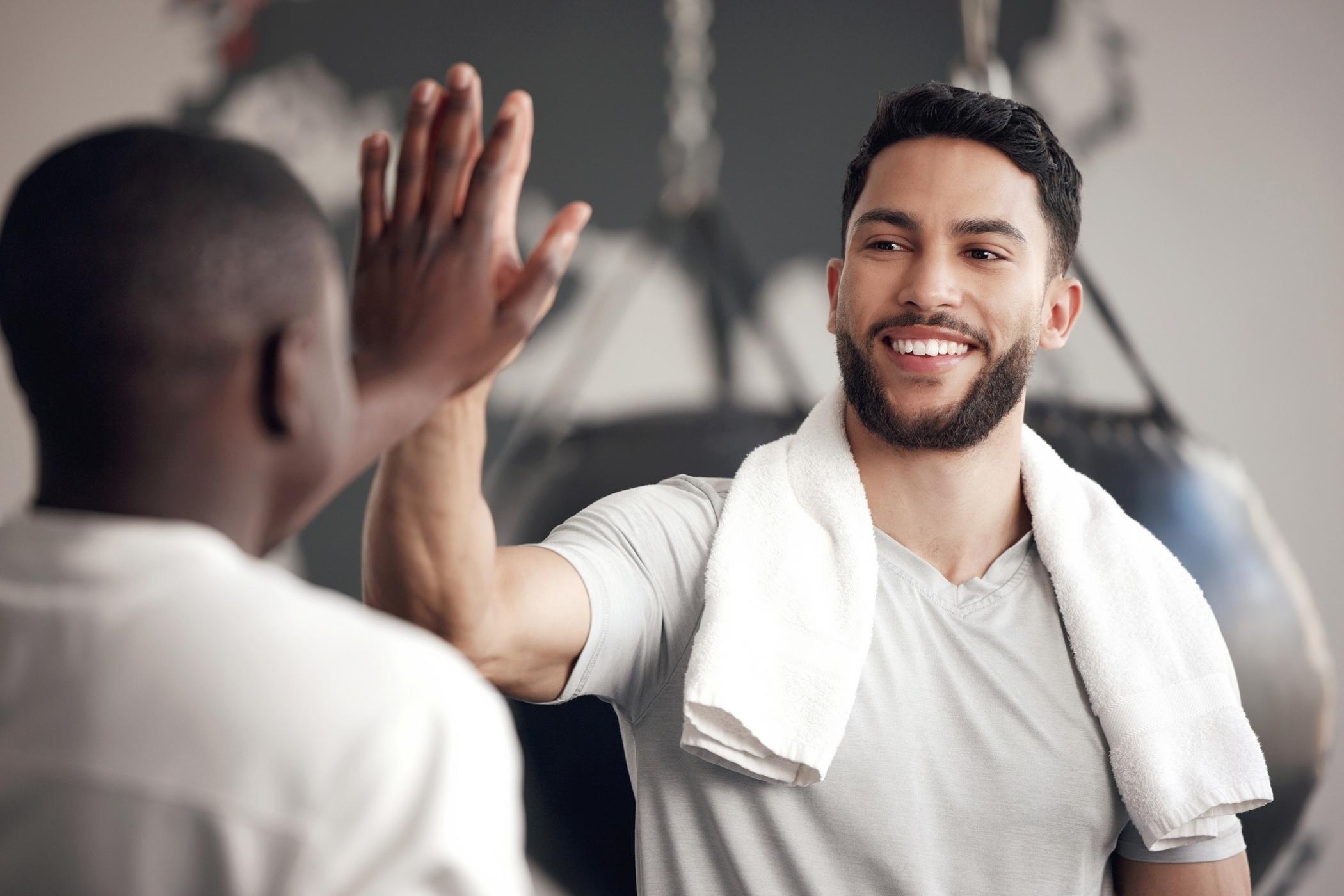 Smiling man giving a high five after exercise, representing confidence, vitality, and men’s sexual health support.