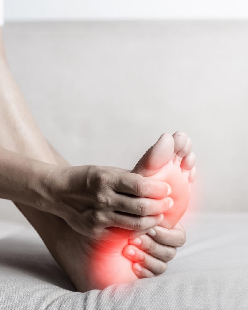 Person holding their foot while experiencing burning foot pain associated with neuropathy.